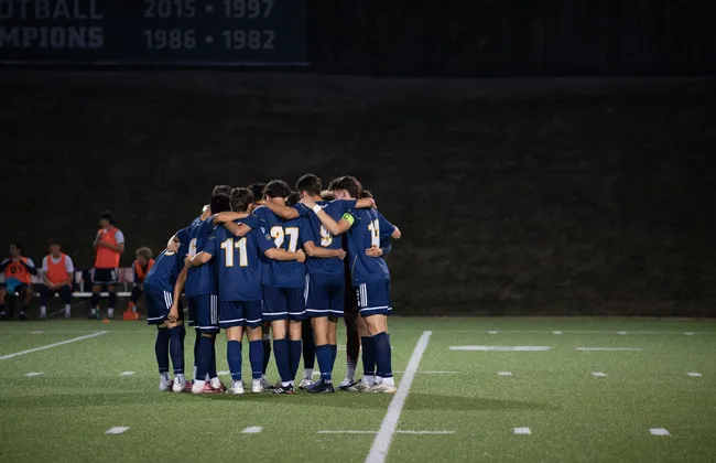 The men's soccer team huddles up on the field