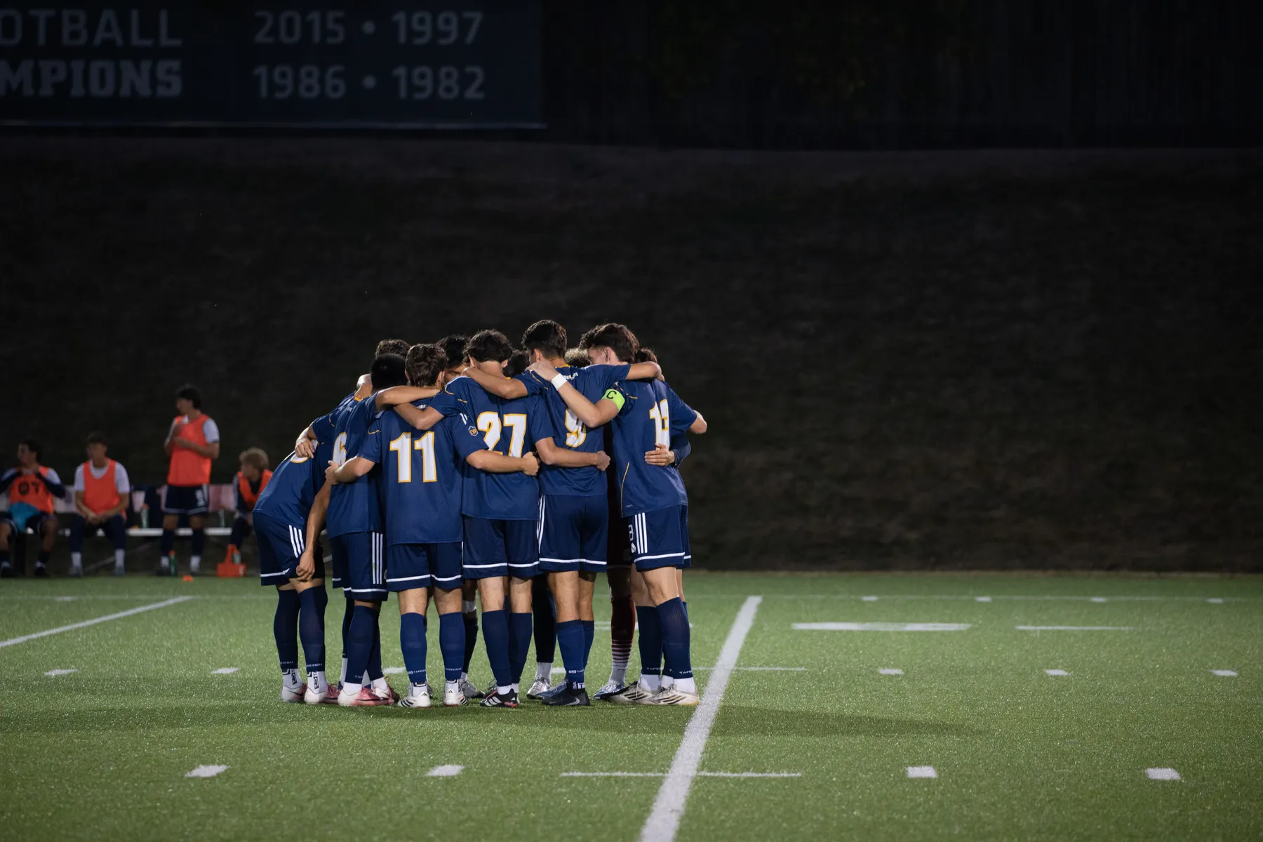 The men's soccer team huddles up on the field