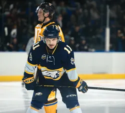 A UBC player skates on the ice with both hands on his stick.