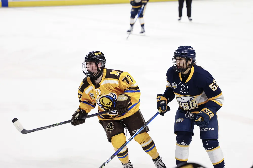Vanessa Schaefer skates next to a Bisons player in the Canada West final.