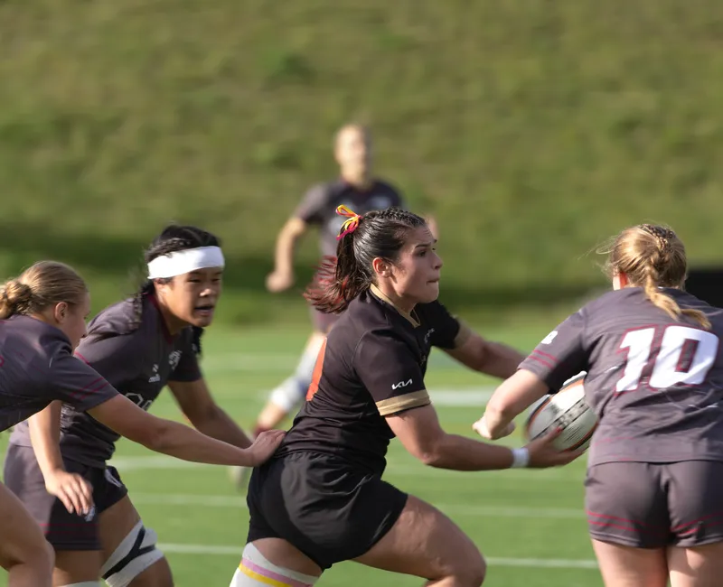 Surrounded by Ottawa players in grey jerseys, a Laval player in a black jersey looks to pass the ball to a teammate.