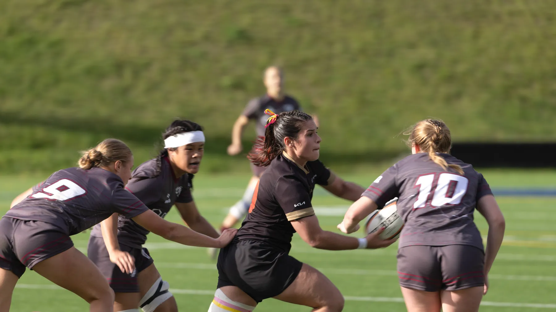 Surrounded by Ottawa players in grey jerseys, a Laval player in a black jersey looks to pass the ball to a teammate.