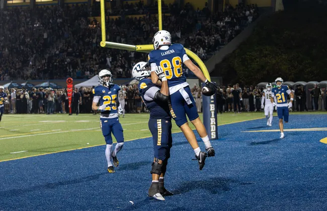A UBC player is held up by another in the end zone.