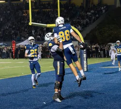 A UBC player is held up by another in the end zone.