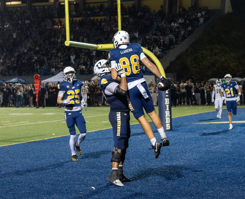 A UBC player is held up by another in the end zone.