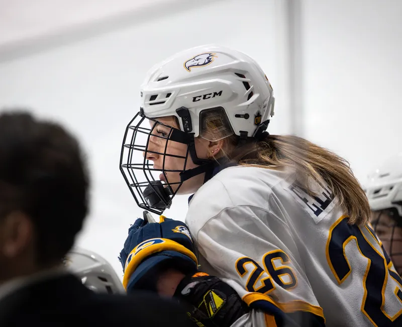 Grace Elliott sits on the bench, with her coach, Graham Thomas, also in view.