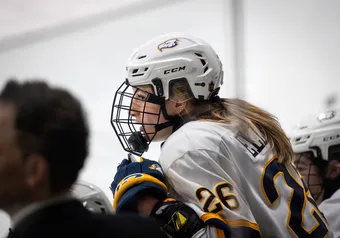 Grace Elliott sits on the bench, with her coach, Graham Thomas, also in view.