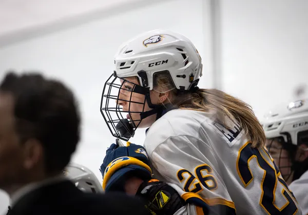 Grace Elliott sits on the bench, with her coach, Graham Thomas, also in view.