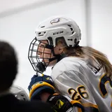 Grace Elliott sits on the bench, with her coach, Graham Thomas, also in view.