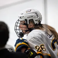 Grace Elliott sits on the bench, with her coach, Graham Thomas, also in view.
