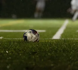 A soccer ball sits still on a turf field.