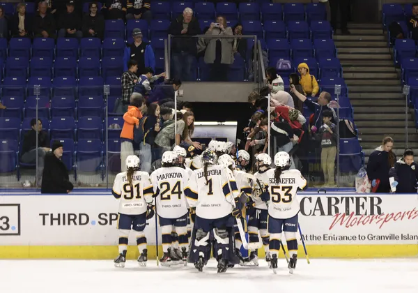 The UBC women's hockey team gathered on the ice near their bench.