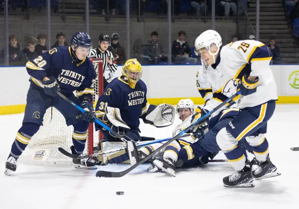 Spartans in blue and T-Birds in white fight for a loose puck in front of the Trinity Western net.