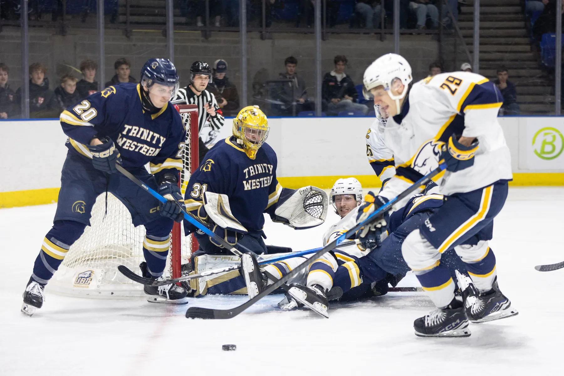 Spartans in blue and T-Birds in white fight for a loose puck in front of the Trinity Western net.
