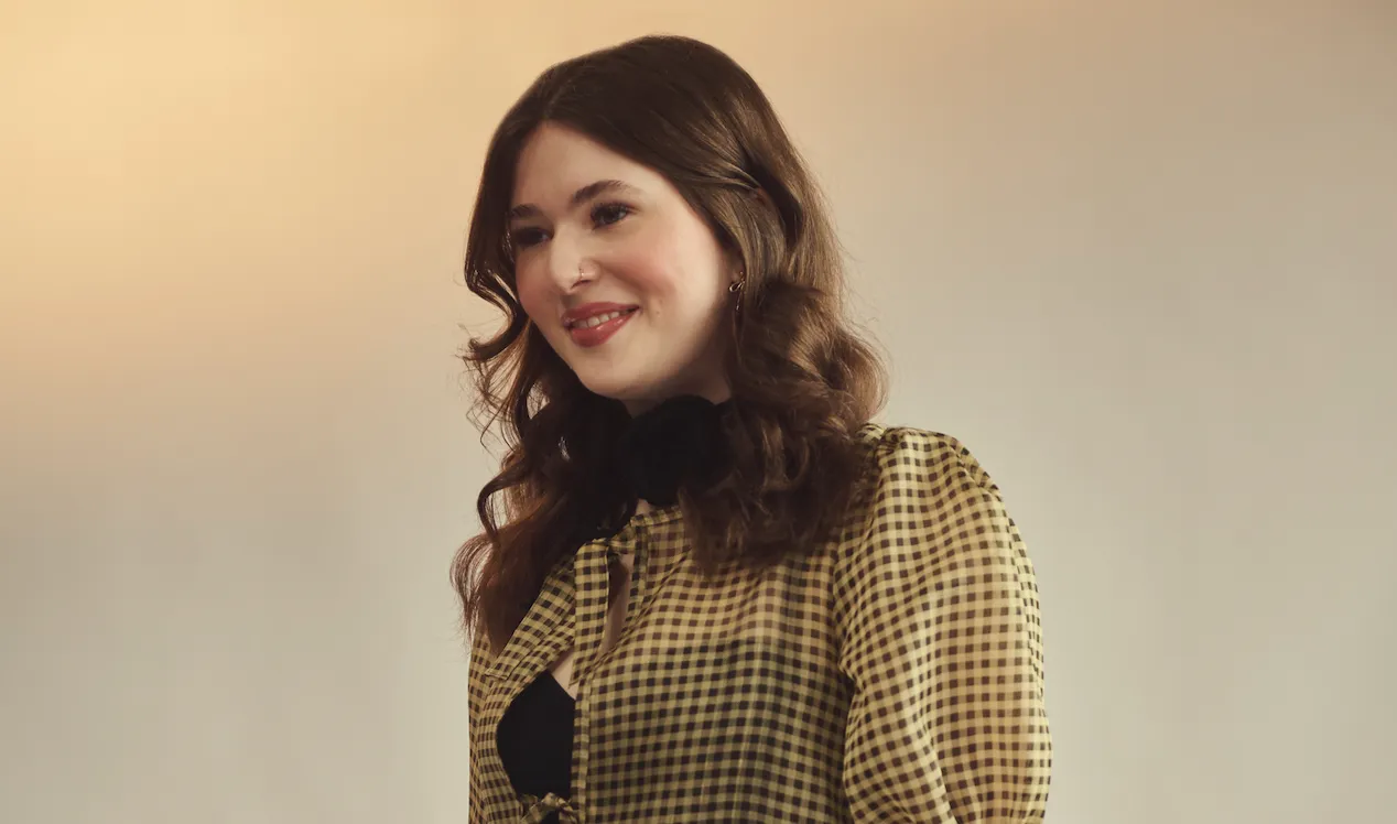 Serena Kealy smiles away from the camera in a black shirt and cream blouse in front of a beige background.