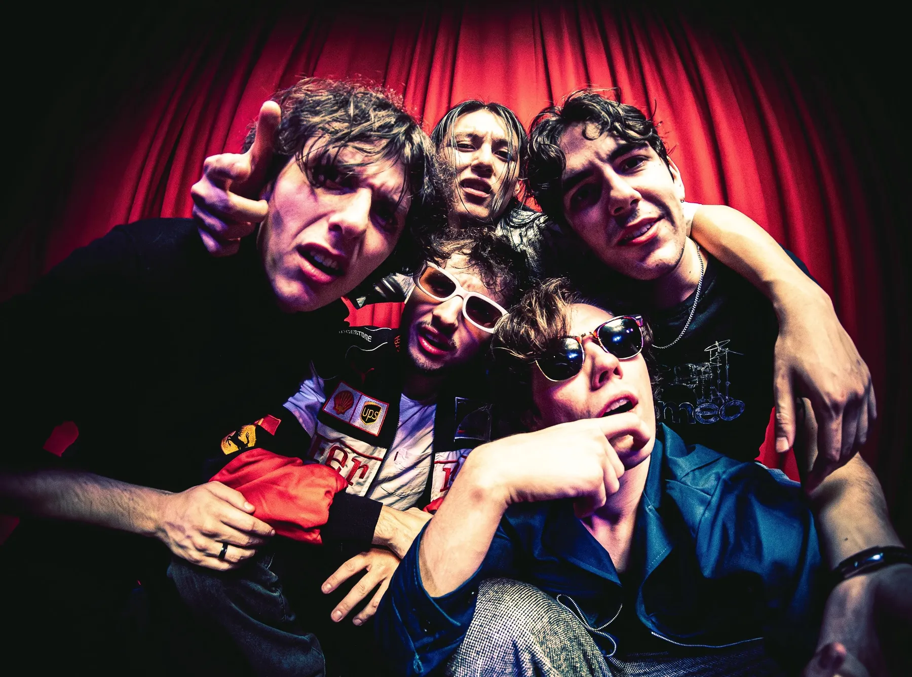 The five members of Chopping Spree stand in front of a red curtain, shot from below using a fisheye lens.