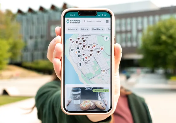 A phone screen showing Campus Nutrition's map feature, with a blurred background of the AMS Nest.