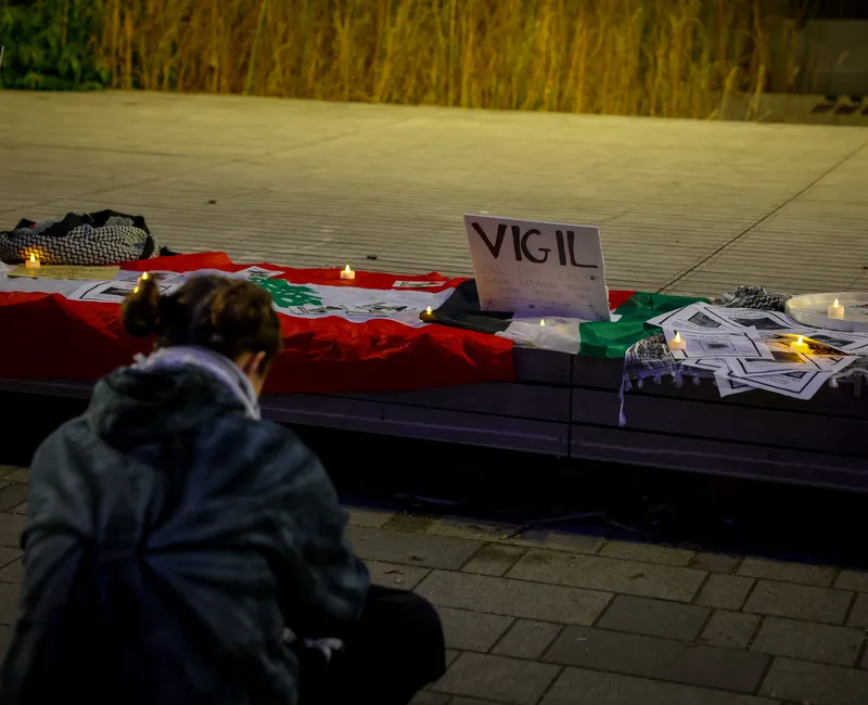 DESCRIPTION PROVIDED BY OPENAI VISION: A vigil held at UBC campus commemorating events in Gaza and Lebanon, featuring flags, candles, and memorial signs.