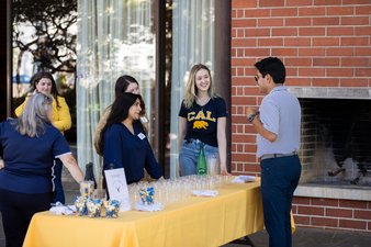 Image of Cal Alumni Association staff and alumni chatting around a table of refreshments.
