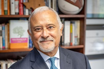 A professional photo of Professor Luis H. Zayas wearing a suit and tie in front of a bookshelf