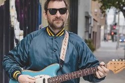 A view of a person playing a blue electric guitar