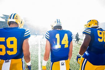 Image of three football players walking onto a football field