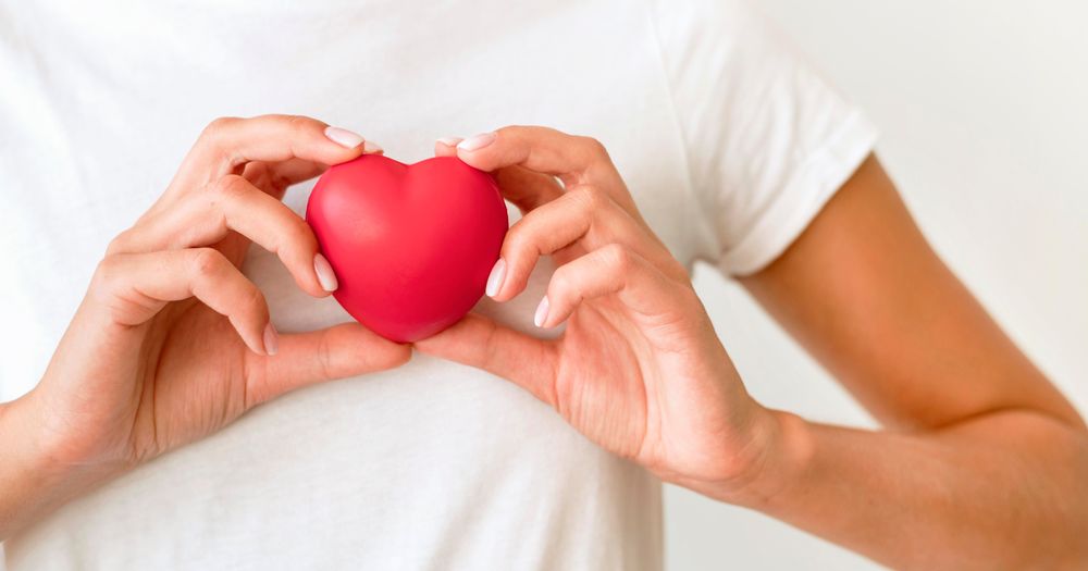 Mujer sosteniendo una forma de corazón contra su pecho