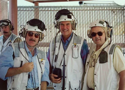 Three men looking at the camera, they have on white construction hats