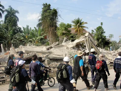Group of volunteers walking in front of Haiti ruins