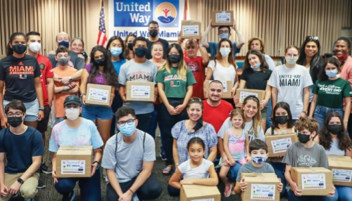 group of people holding boxes labeled with the united way miami logo