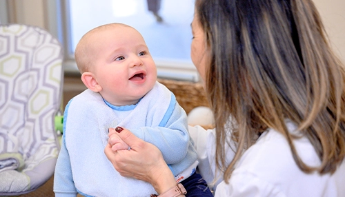 baby smiling at woman who is holding him