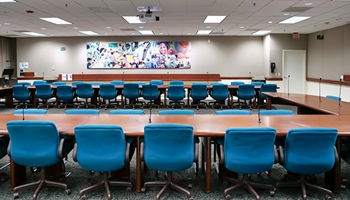 photograph of meeting room with microphones, flags and united way logo