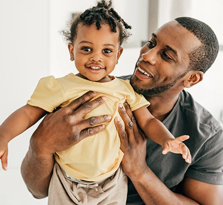 man showing his daughter to the camera while both smiling