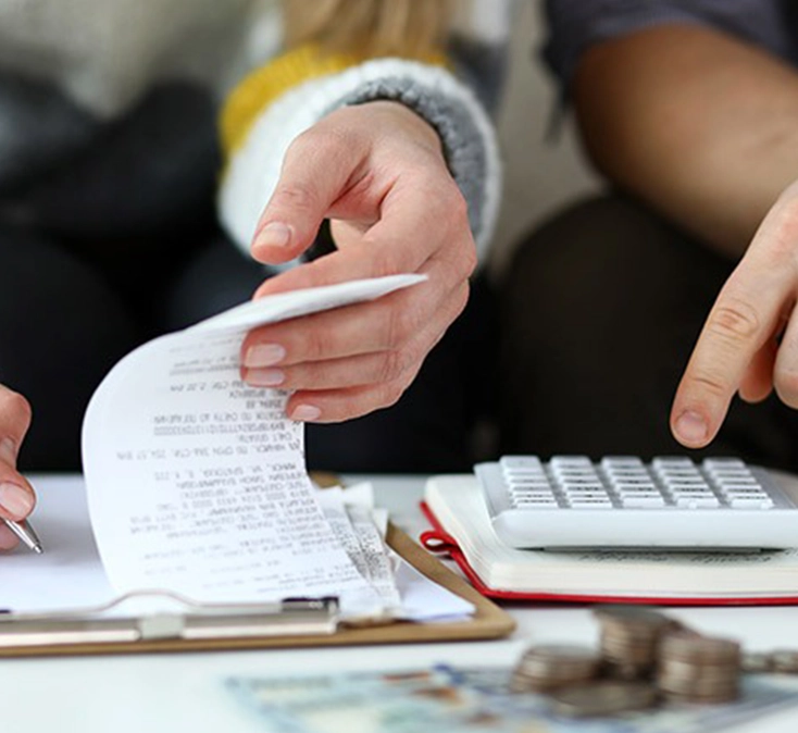 close-up of hands writing and doing calculations on calculator