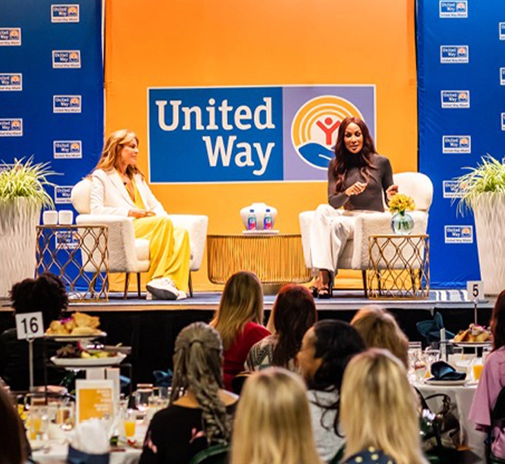 two women giving a talk to a group of people from a stage