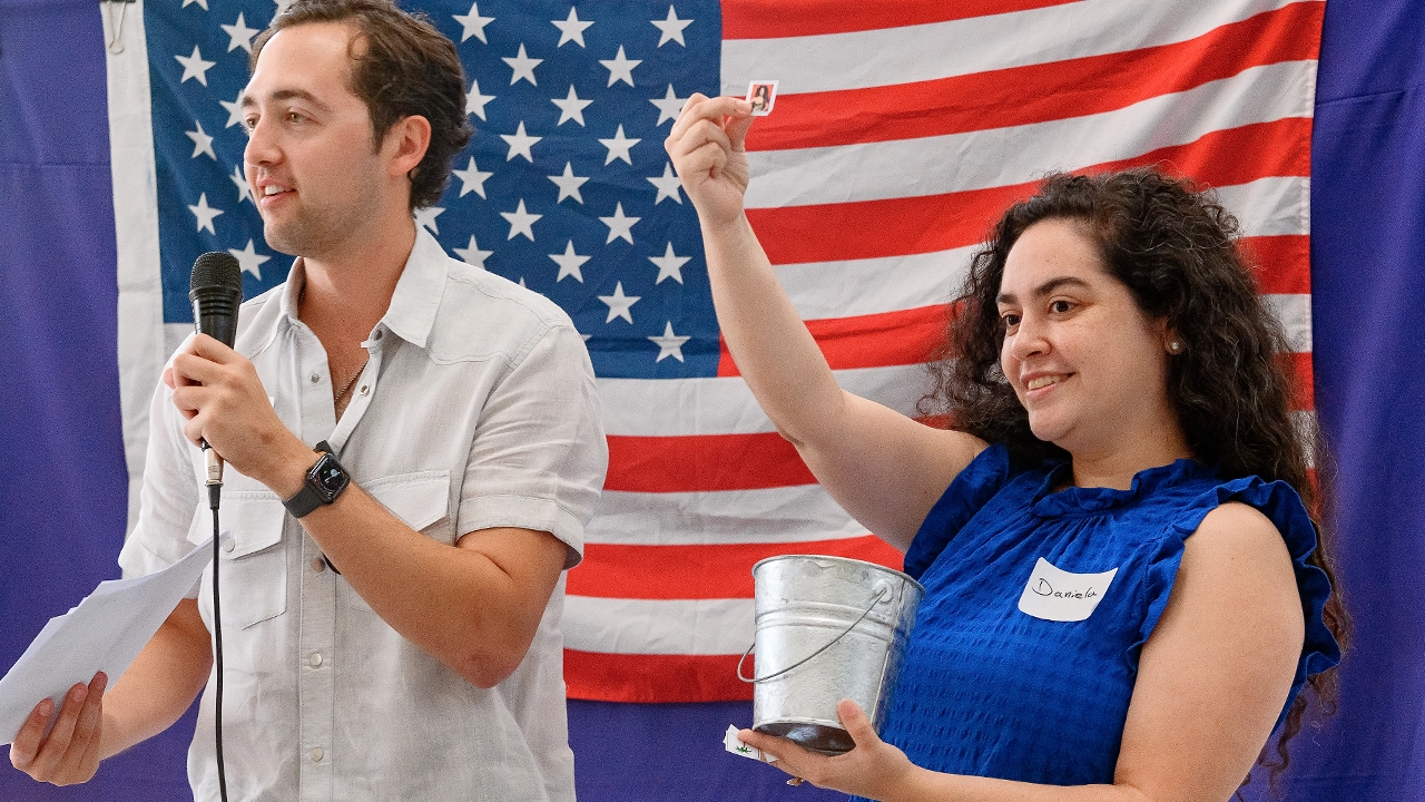 two people talking into a microphone with the american flag behind them