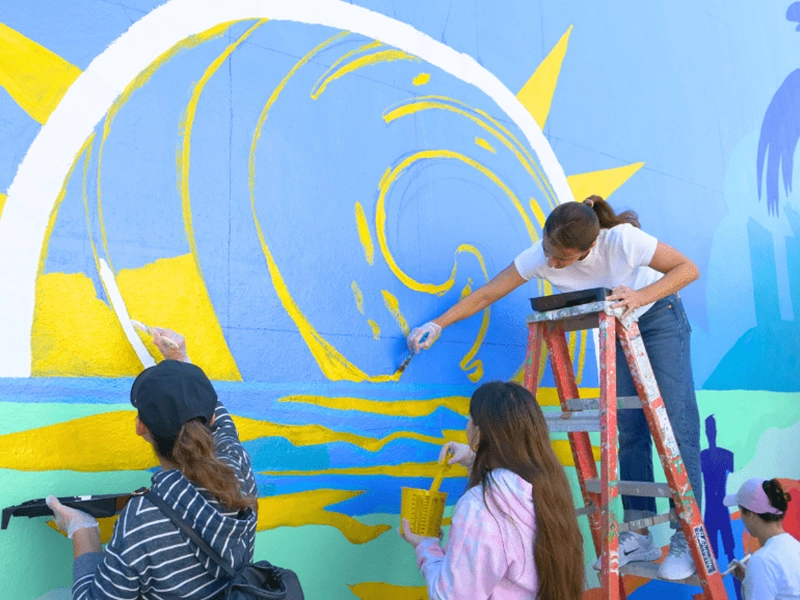 three women painting a mural