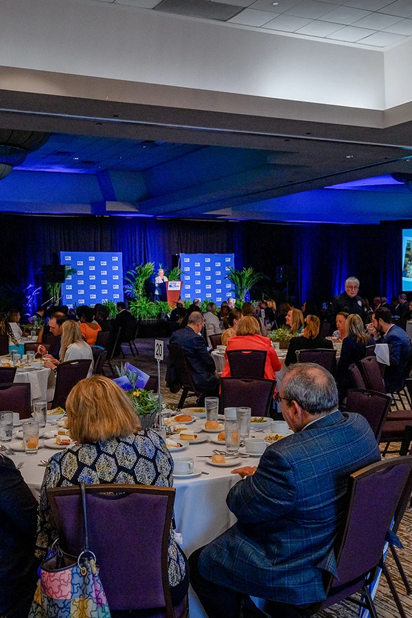 A large event room with people sitting around tables