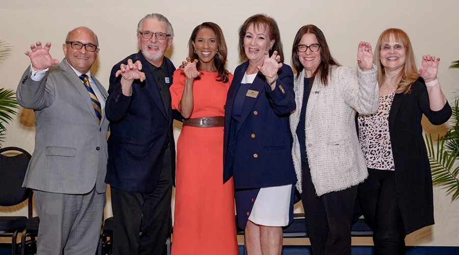 A group of people standing together, they are doing a panther hand sign