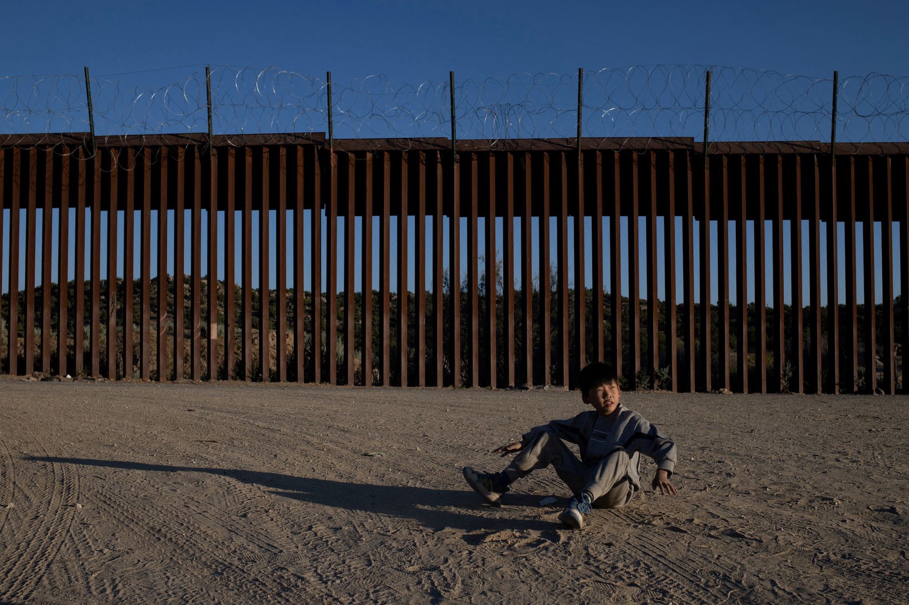 Zhu, a 10-year-old asylum-seeking migrant from Henan Province, China, plays near the border wall after his family crossed into the United States from Mexico in Jacumba Hot Springs, California, U.S., May 13, 2024. REUTERS/Adrees Latif     TPX IMAGES OF THE DAY     