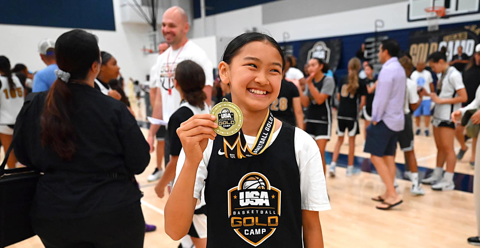 A girl holds up a Gold Camp Medal