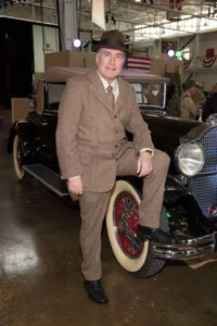 adult man dressed in suit with car behind