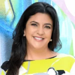 Headshot of a woman, she smiles at the camera, she has long dark hair