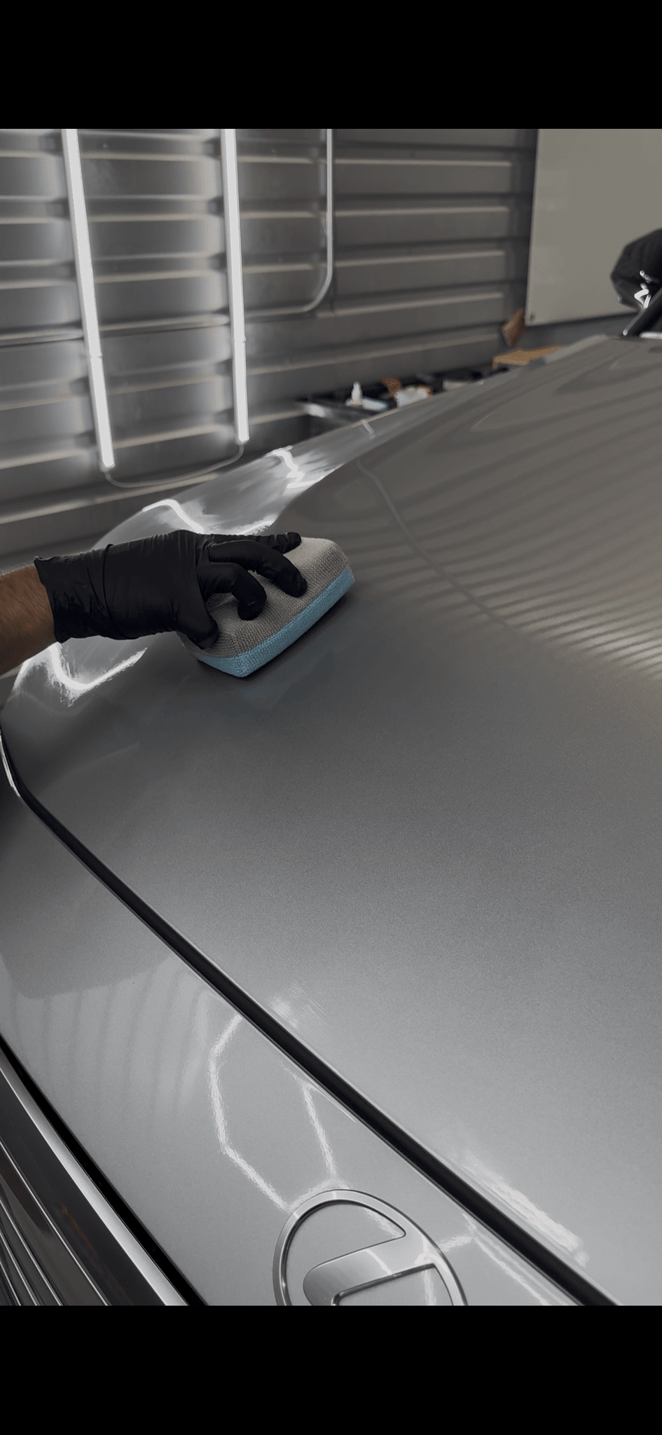 Gloved hand applying paint sealant to a silver hood during an exterior detail at the Boerne, TX shop