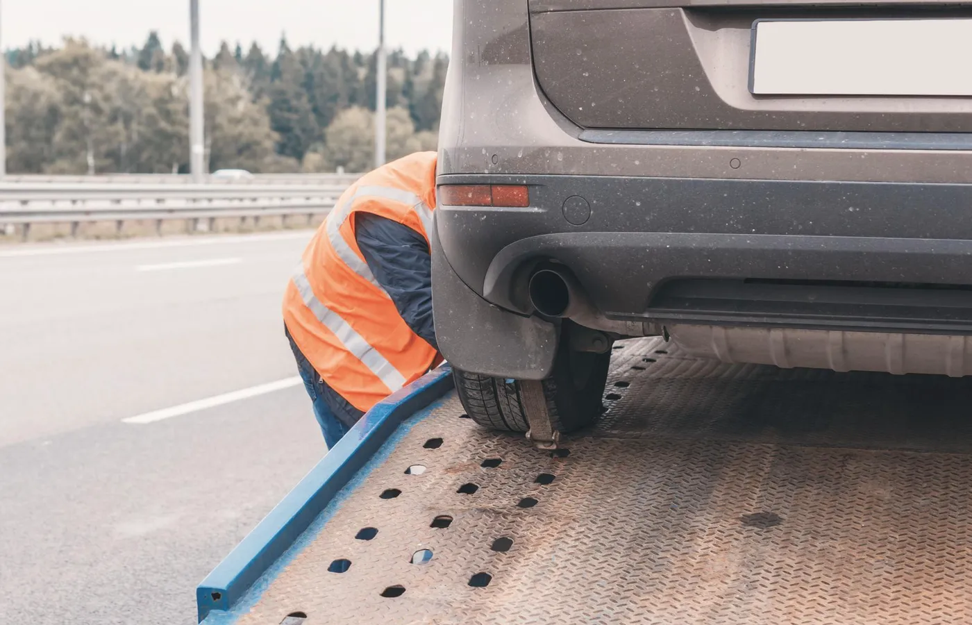 Pracownik pomocy drogowej wciąga auto na lawetę