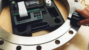 A quality manager measures properties of a steel flange