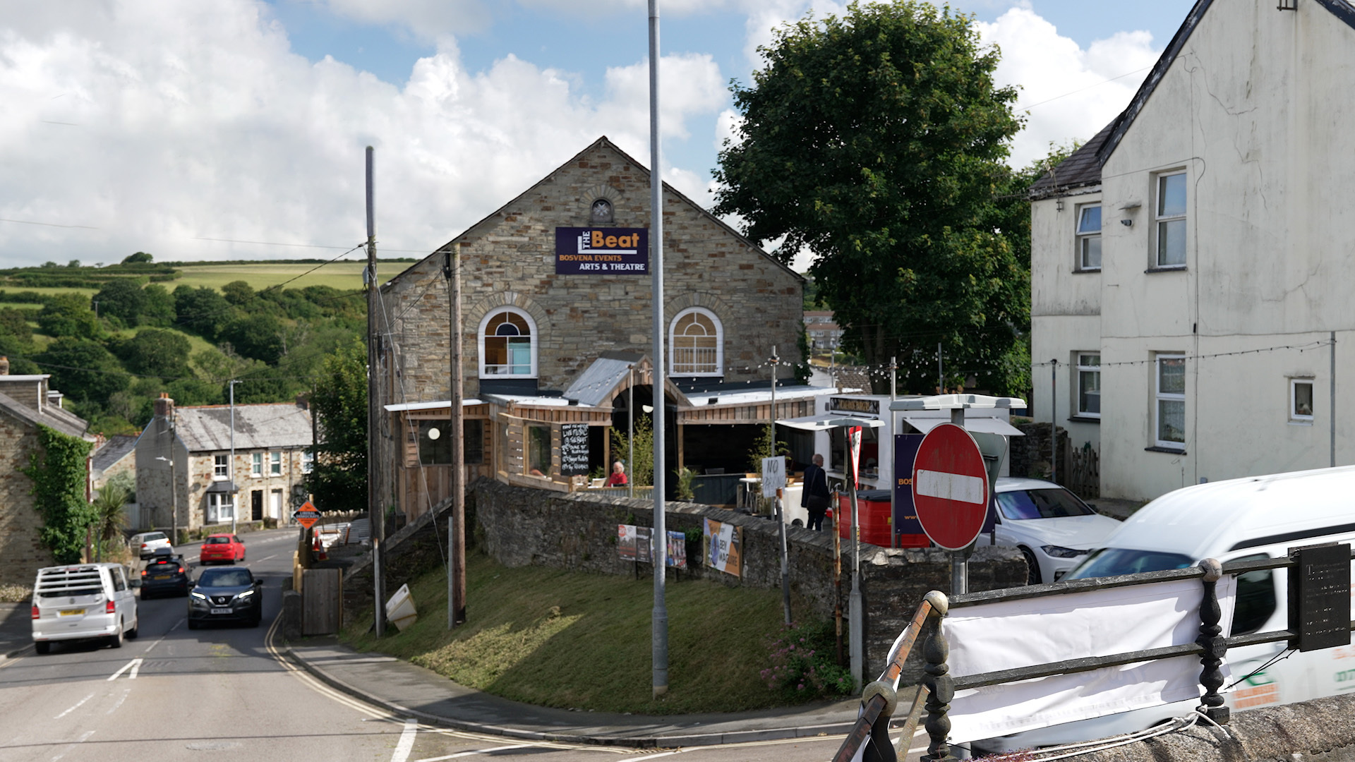 An arts and theatre venue on the corner of a road. It has a sign that says 'The Beat Arts & Theatre' and a food truck, seating outside the front entrance.