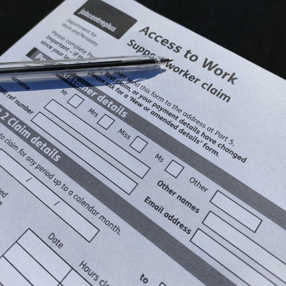 A photograph of the Access to Work application form with a pen resting on top