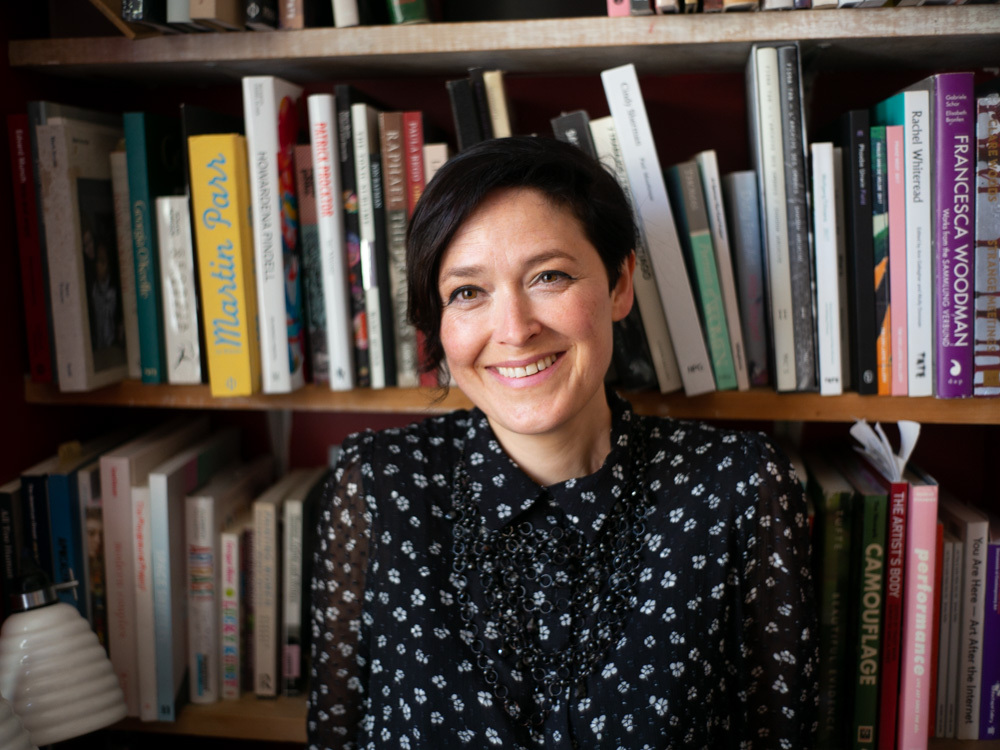 A portrait of a white woman with short dark hair in a dark patterned top