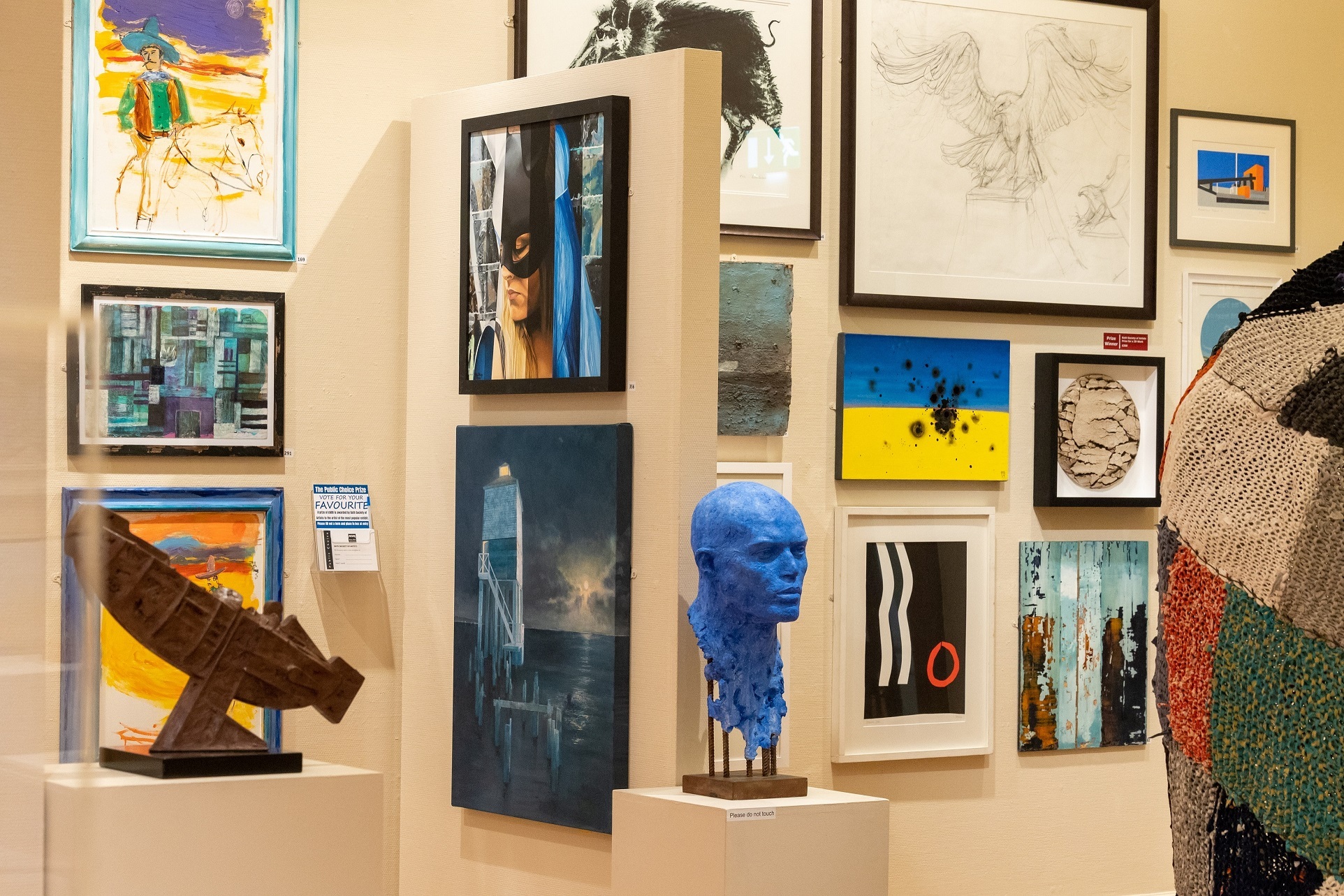 A photo of last year's exhibition, showing a selection of pictures on the wall, and sculptures in the foreground